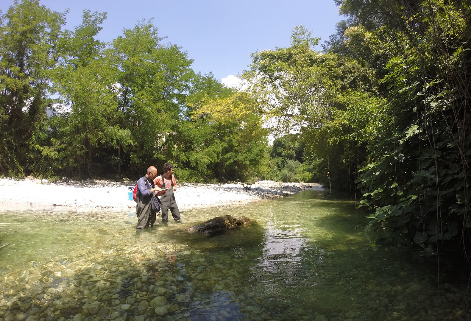 Two men stand in creek recording Geomorphological observations